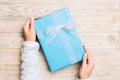 Top view woman hands holding present box with colored bow on yellow rustic wooden background with copy space Royalty Free Stock Photo