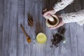 Top view of woman hands with ingredients on table, wooden mortar, yellow turmeric, clove and green natural leaves. Close up,