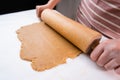 Top view of woman hands rolling out the dough with a wooden rolling pin for cookies from the shortcrust pastry