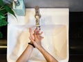 Top view of woman hands washing her hands above the sink with soap and water in washing room Royalty Free Stock Photo