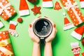 Top view of woman holding a cup of coffee in her hands on green background. Christmas decorations. New year time concept Royalty Free Stock Photo