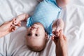 View of woman holding hands of infant in blue bodysuit