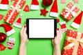 Top view of woman holding tablet in her hands on green background made of Christmas decorations. New Year holiday concept. Mockup Royalty Free Stock Photo