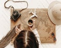 Top view of woman holds cup of black coffee over vintage world map with traveler accessories Royalty Free Stock Photo