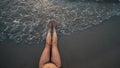 Woman legs on beach splashed by waves at sunset Royalty Free Stock Photo