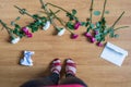 Top view of woman legs standing on the floor with crumpled paper of letter among scattered flowers. breakup. bad Valentine`s day.