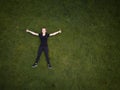 Woman lying on a green grass filed with arms spreaded