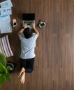 Top view woman lying working on laptop on wooden floor