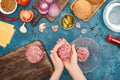 Top view of woman making cutlets for fresh burgers near ingredients on blue textured surface