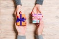 Top view of a woman and a man exchanging gifts on wooden background. Couple give presents to each other. Close up of making Royalty Free Stock Photo