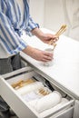 Woman organizing environmental bathroom amenities in drawer and putting bamboo toothbrush into a cup