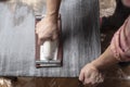 Top view on woman prepares the surface for painting and sanding by hands an old wooden black table