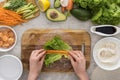 Top view of woman putting cut carrot on lettuce, on cutting board. Royalty Free Stock Photo