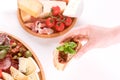 Top view on woman`s hand holding bruschetta with sun dried tomatoes above table with traditional antipasti plates