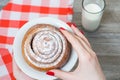 Top view of woman`s hand holding a cinnamon roll with powdered s Royalty Free Stock Photo