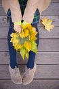 Top view on woman`s hands holding beautiful bunch of yellow marple leaves. Young woman with bouquet of autumn leaves