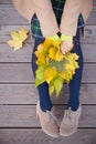 Top view on woman's hands holding beautiful bunch of yellow marple leaves. Young woman with bouquet of autumn leaves