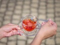 A female`s hands with a cup of berries liquid on a stone blurred background. Delicious and natural strawberry tea. Royalty Free Stock Photo