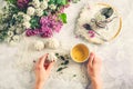 Top view woman`s hands holding vintage cup of green tea and meringue cake on the white table with a bouquet of blossoming lilacs