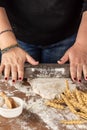 Top view of woman`s hands kneading pizza dough with rolling pin, on wooden table with flour, salt and wheat, selective focus, bla Royalty Free Stock Photo