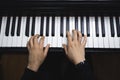 Top view of woman's hands playing piano by reading sheet music. Dark mood. Royalty Free Stock Photo