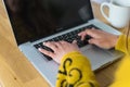 Top view of a woman`s hands typing on a laptop computer, on a wooden countertop as background and a mug on the side. Royalty Free Stock Photo