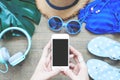 Top view of woman`s hands using smartphone with summer items on