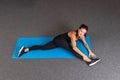 Top view of woman in sports black clothing at the gym doing stretching exercises on the blue yoga mat