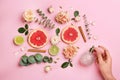 Top view of woman spraying perfume on pink background, flowers and citrus fruits representing aroma Royalty Free Stock Photo