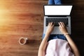 Top view of woman typing on laptop computer with blank white screen from home on wooden floor with copy space. Royalty Free Stock Photo