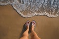 Top view of woman wearing beach slippers on sandy seashore, closeup Royalty Free Stock Photo