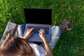 Top view. Woman working on laptop pc computer with blank black empty screen to copy space in park on green grass Royalty Free Stock Photo