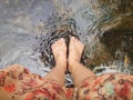 Top view of women leg and feet dip in crystalline stream