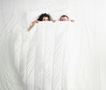 Woman and man peeking on each other under white blanket, awake couple in bed Royalty Free Stock Photo