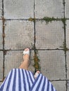 Top view of women's fashionable legs in trendy white jeans in stylish red-black summer shoes on a stone tile on the street Royalty Free Stock Photo