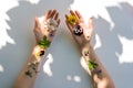 Top view women`s hands with multicolored flowers on white background with shadow, art femininity, connecting with nature Royalty Free Stock Photo