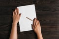 Top view of women`s hands, ready to write something on an empty piece of paper lying on a wooden table. White blank sheet of pape Royalty Free Stock Photo