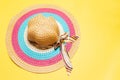 Top view of women summer hat with ribbon bow and lines of white, pink and blue colors on yellow background. Royalty Free Stock Photo