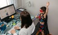 Woman working from home with her daughter singing by her side