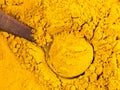 Top view of wood spoon on Turmeric powder closeup