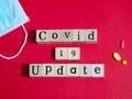 Top view of wooden block with word Covid-19 Update on red texture background