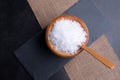 Top view of a wooden bowl full of sea salt on a black stone board Royalty Free Stock Photo