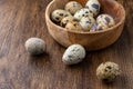 Top view of wooden bowl with speckled quail eggs on dark wooden table horizonta