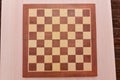 Top view on wooden chess board on light wooden table background Royalty Free Stock Photo
