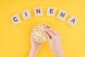 Top view of wooden cubes with cinema lettering and hands holding bucket and taking popcorn isolated Royalty Free Stock Photo