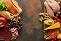 Top view of wooden cutting board with raw meat, fish, poultry, cheese, fruits, vegetables and peanuts neaon dark brown Royalty Free Stock Photo