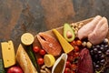 Top view of wooden cutting board with raw meat, fish, poultry, cheese, fruits, vegetables and peanuts near fresh Royalty Free Stock Photo