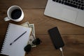 Top view of wooden desk with objects. Laptop, notebook, coffee cup, money, pen and sunglasses. Royalty Free Stock Photo