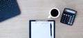 Top view of wooden desk table with laptop keyboard, coffee cup, calculator and blank sheet of paper. Royalty Free Stock Photo