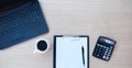 Top view of wooden desk table with laptop keyboard, coffee cup, calculator and blank sheet of paper. Royalty Free Stock Photo